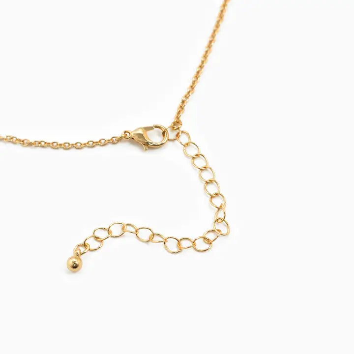 Close-up of a gold chain necklace with a lobster clasp, adjustable link extension chain, and a small dangling bead on a white background.