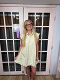 A woman wearing the Sloane dress, with a textured material, collared neck, ruffle trim in a camel color. 