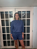 The Terri Set is a blue indigo scuba pullover and shorts duo. The pullover features a relaxed fit with approximately 23.75" total body length and 44" bust. The matching shorts offer a 25.5" waist and 3.5" inseam.