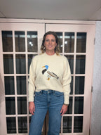 A woman wearing The Layla Sweater crafted from soft heathered knit fabric, features a relaxed fit ,crew neckline and long sleeves with a duck intarsia graphic at the front 