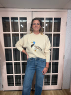 A woman wearing The Layla Sweater crafted from soft heathered knit fabric, features a relaxed fit ,crew neckline and long sleeves with a duck intarsia graphic at the front 