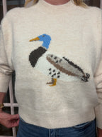 A woman wearing The Layla Sweater crafted from soft heathered knit fabric, features a relaxed fit ,crew neckline and long sleeves with a duck intarsia graphic at the front 