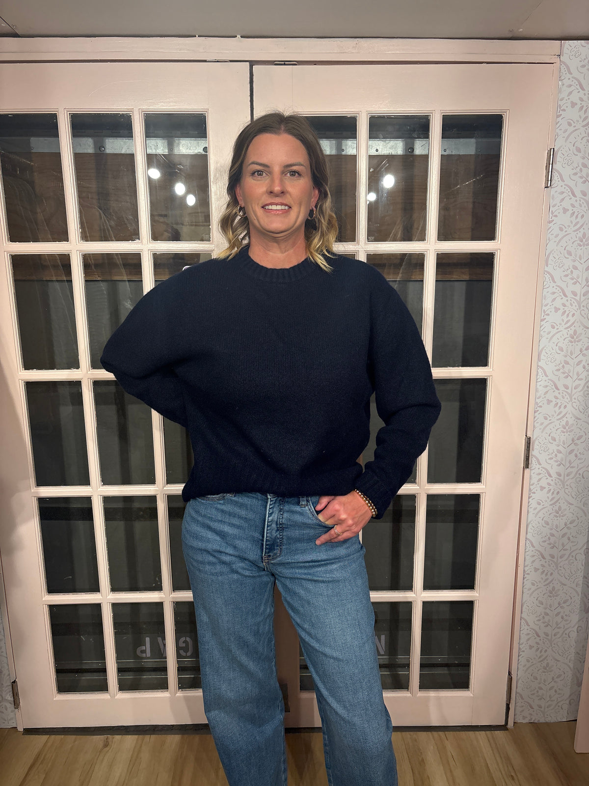 A woman wearing The Lennon Sweater that is a relaxed knit sweater with a soft brushed marled texture and crew neckline. Long sleeves, dropped shoulders, and wide ribbed trim at the cuffs and hem