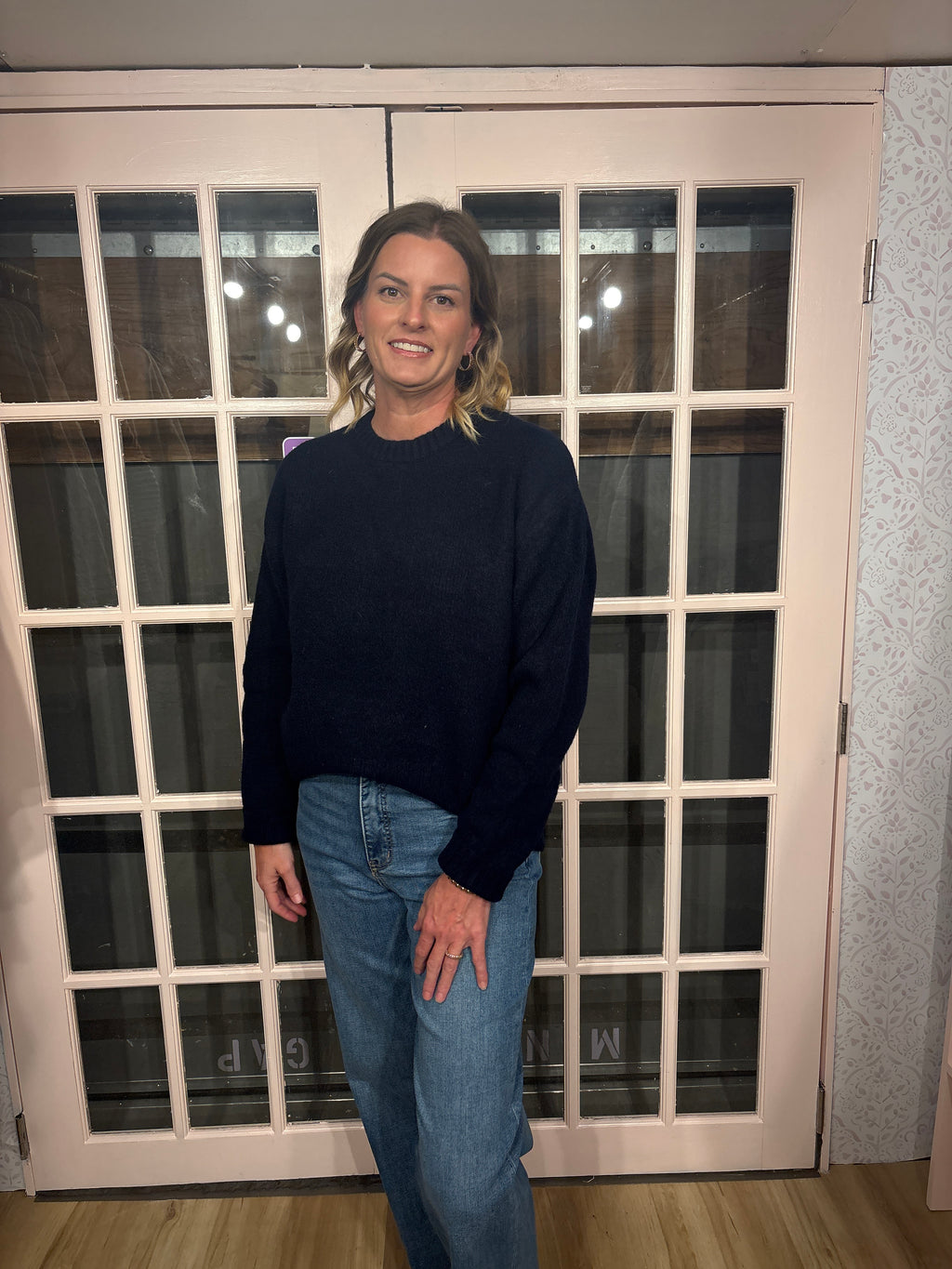 A woman wearing The Lennon Sweater that is a relaxed knit sweater with a soft brushed marled texture and crew neckline. Long sleeves, dropped shoulders, and wide ribbed trim at the cuffs and hem