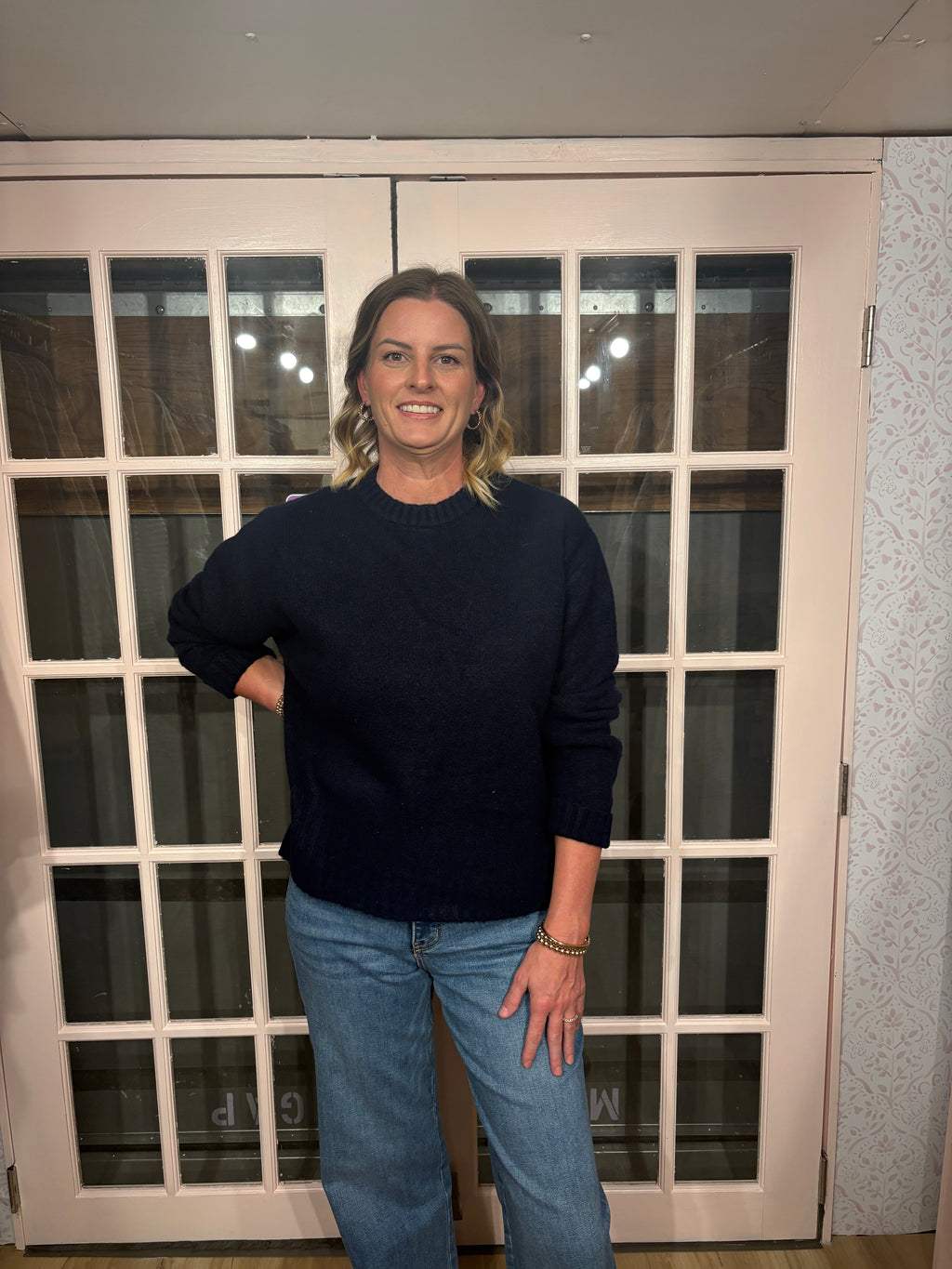 A woman wearing The Lennon Sweater that is a relaxed knit sweater with a soft brushed marled texture and crew neckline. Long sleeves, dropped shoulders, and wide ribbed trim at the cuffs and hem