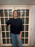 A woman wearing The Lennon Sweater that is a relaxed knit sweater with a soft brushed marled texture and crew neckline. Long sleeves, dropped shoulders, and wide ribbed trim at the cuffs and hem