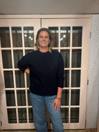 A woman wearing The Lennon Sweater that is a relaxed knit sweater with a soft brushed marled texture and crew neckline. Long sleeves, dropped shoulders, and wide ribbed trim at the cuffs and hem