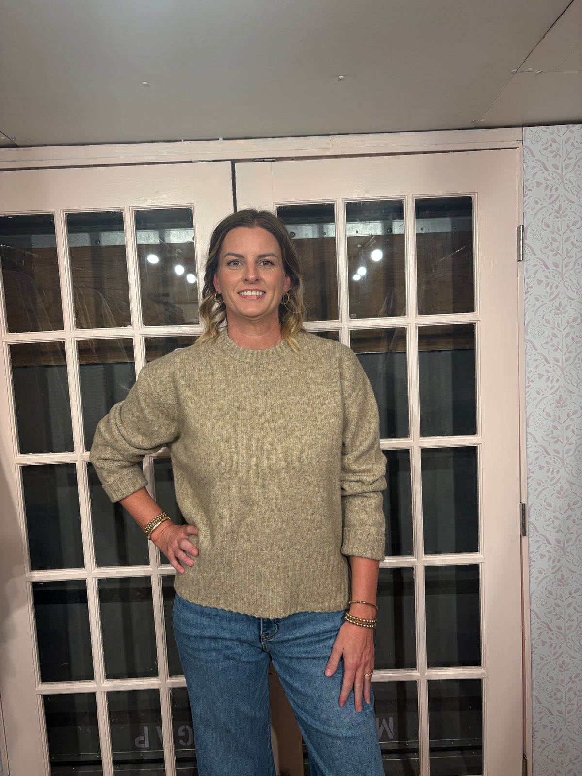 A woman wearing The Lennon Sweater that is a relaxed knit sweater with a soft brushed marled texture and crew neckline. Long sleeves, dropped shoulders, and wide ribbed trim at the cuffs and hem