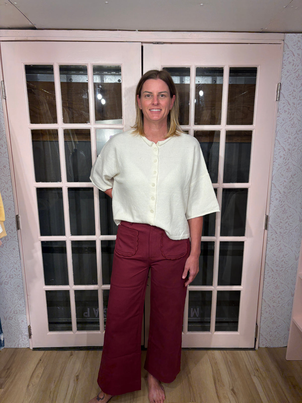 A woman wearing the Denise Pants in burgundy with a flattering high rise fit and a relaxed wide leg silhouette