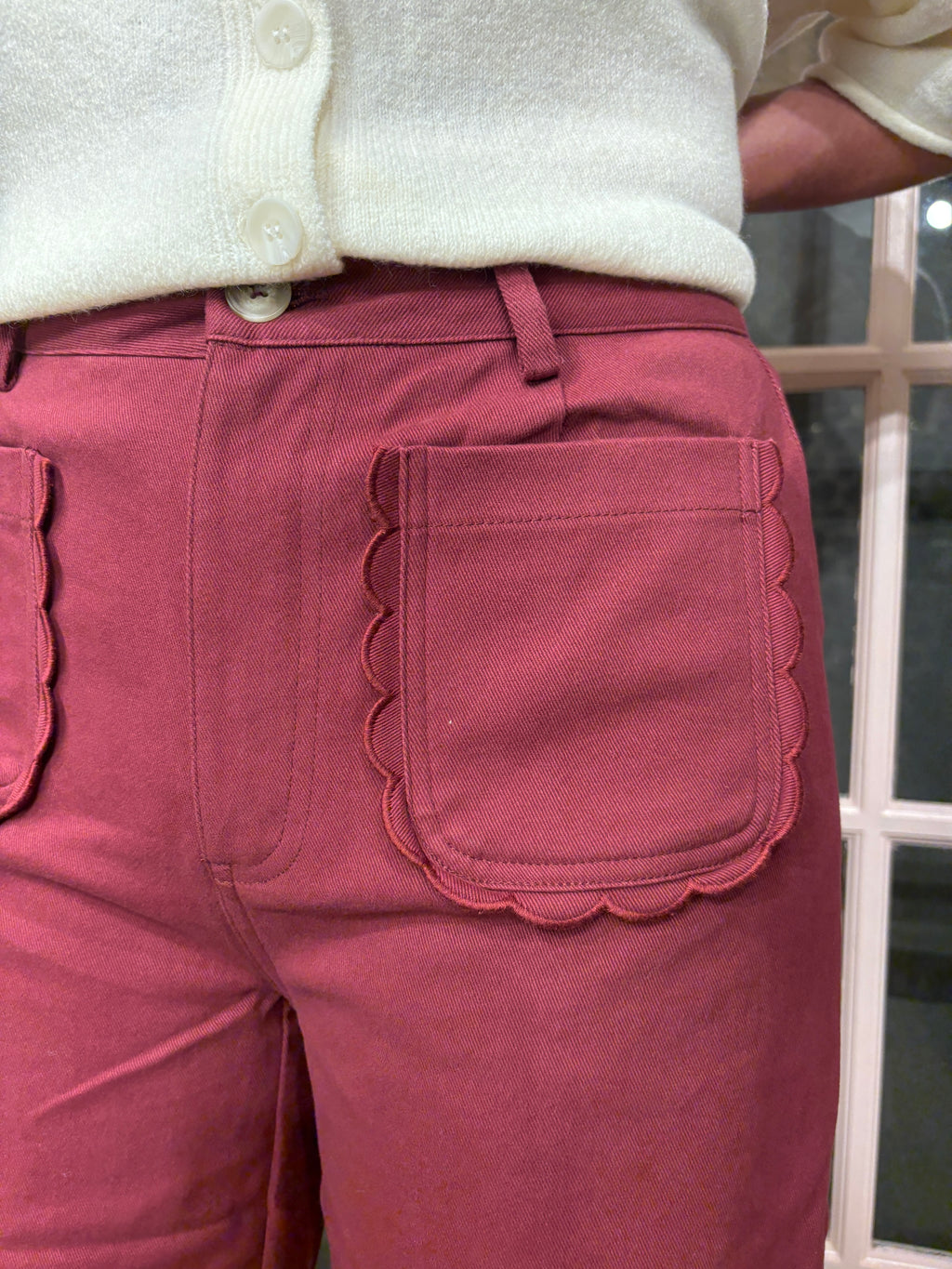 A woman wearing the Denise Pants in burgundy with a flattering high rise fit and a relaxed wide leg silhouette