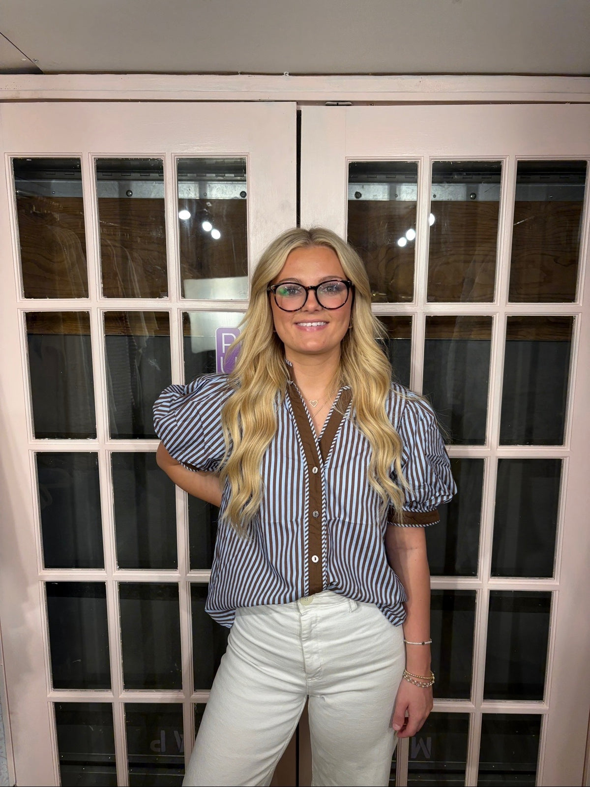 A woman wearing the Bri Blouse in brown and blue with a flattering V neckline, contrast trim, and statement puff sleeves