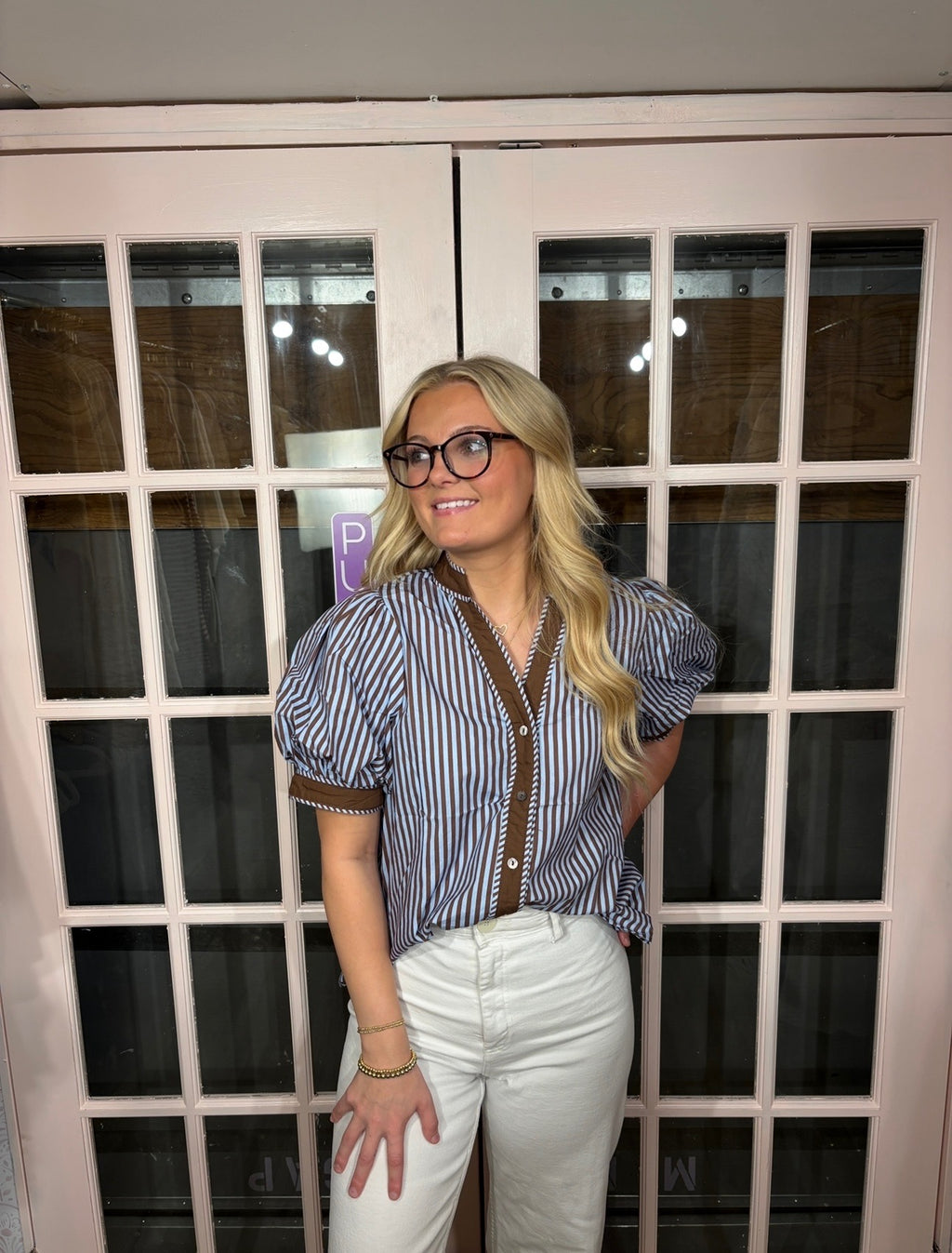A woman wearing the Bri Blouse in brown and blue with a flattering V neckline, contrast trim, and statement puff sleeves