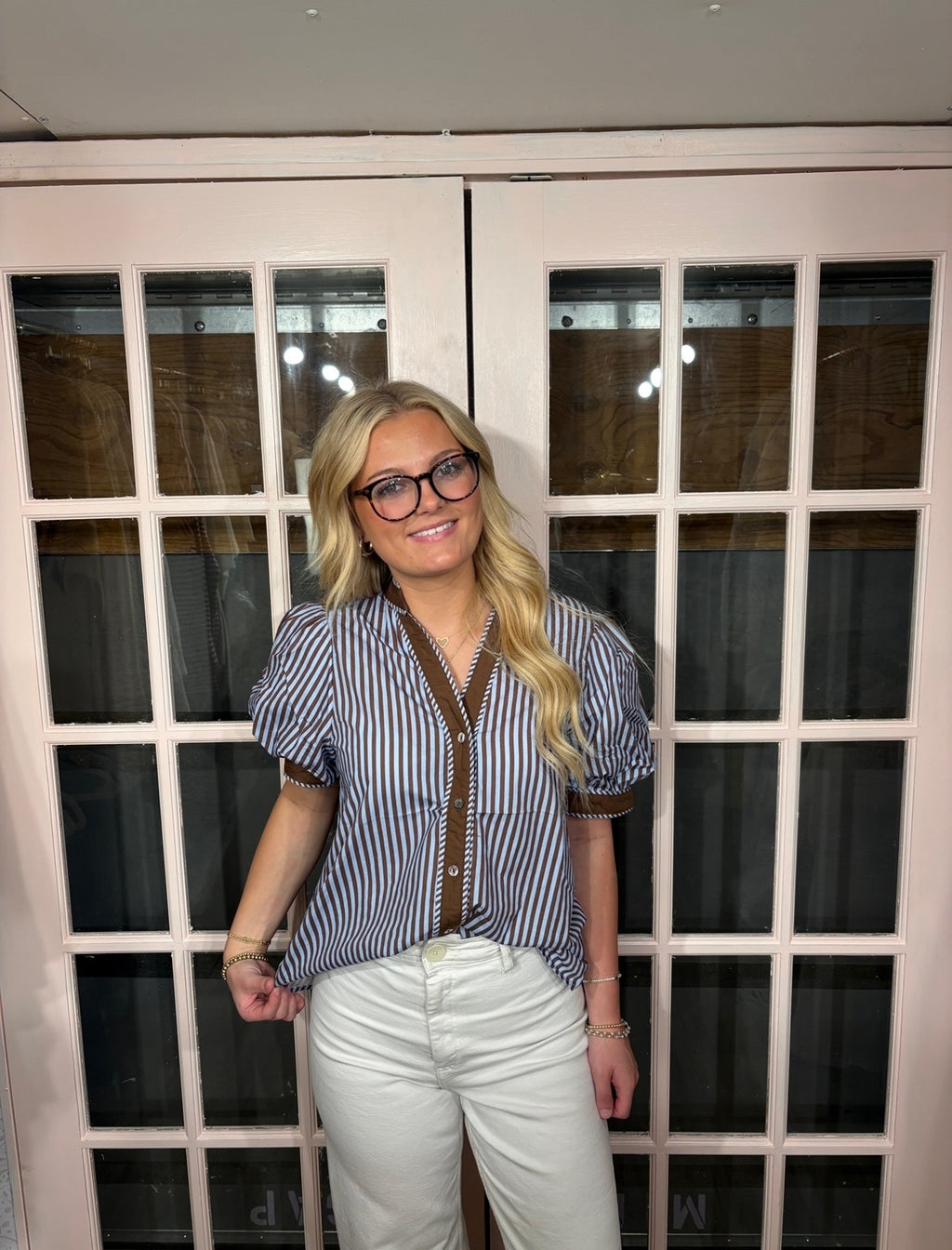 A woman wearing the Bri Blouse in brown and blue with a flattering V neckline, contrast trim, and statement puff sleeves