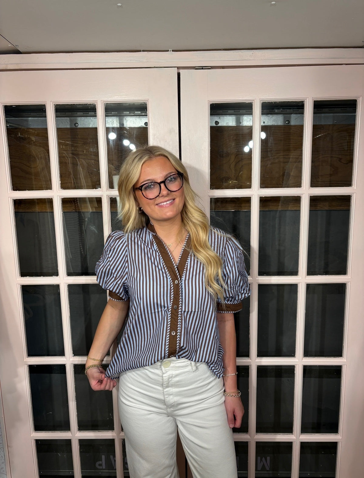 A woman wearing the Bri Blouse in brown and blue with a flattering V neckline, contrast trim, and statement puff sleeves