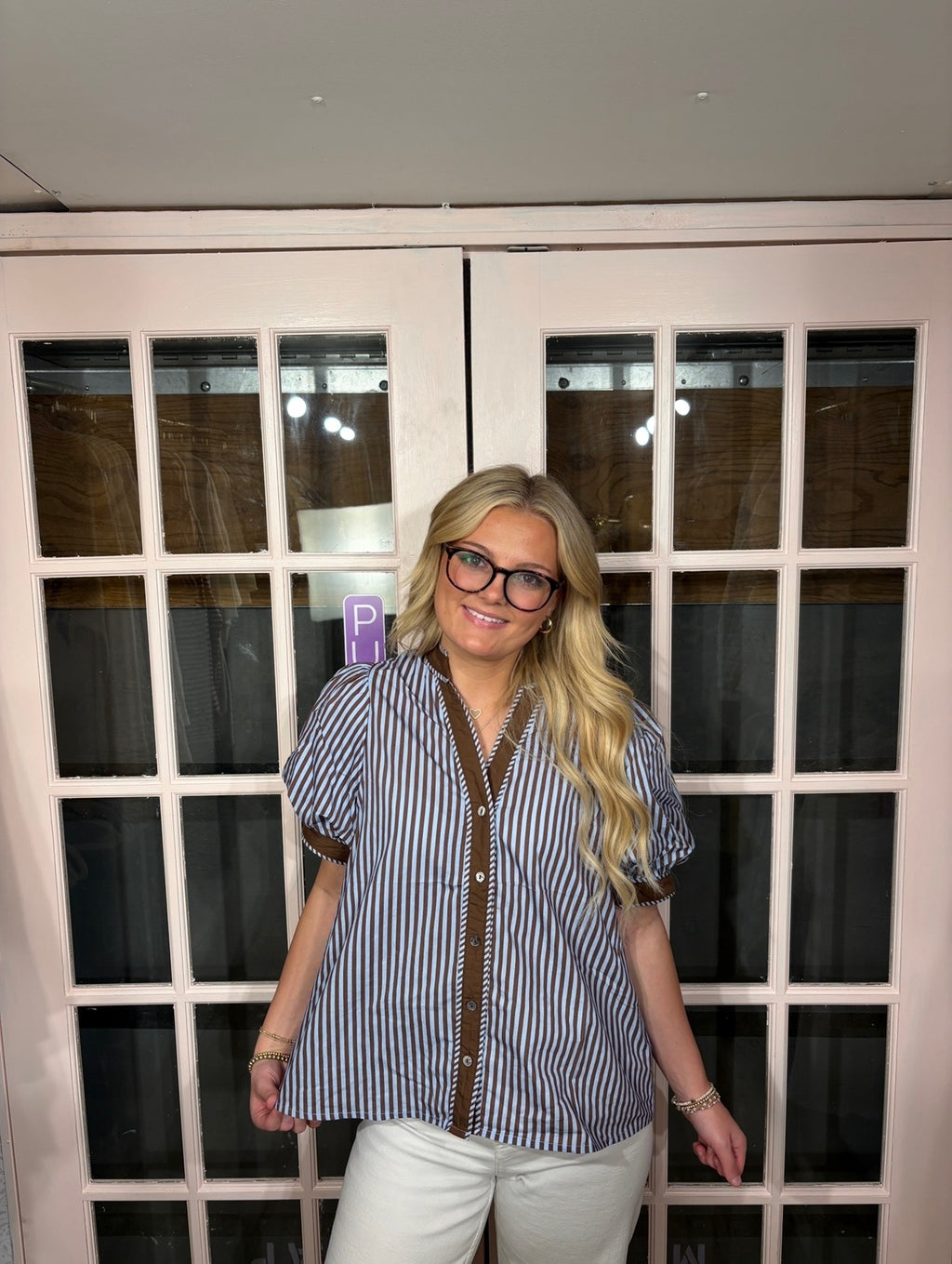 A woman wearing the Bri Blouse in brown and blue with a flattering V neckline, contrast trim, and statement puff sleeves