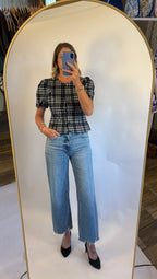 A woman wearing the Madilyn blouse in a blue plaid featuring a puff sleeve, button front and fitted silhouette