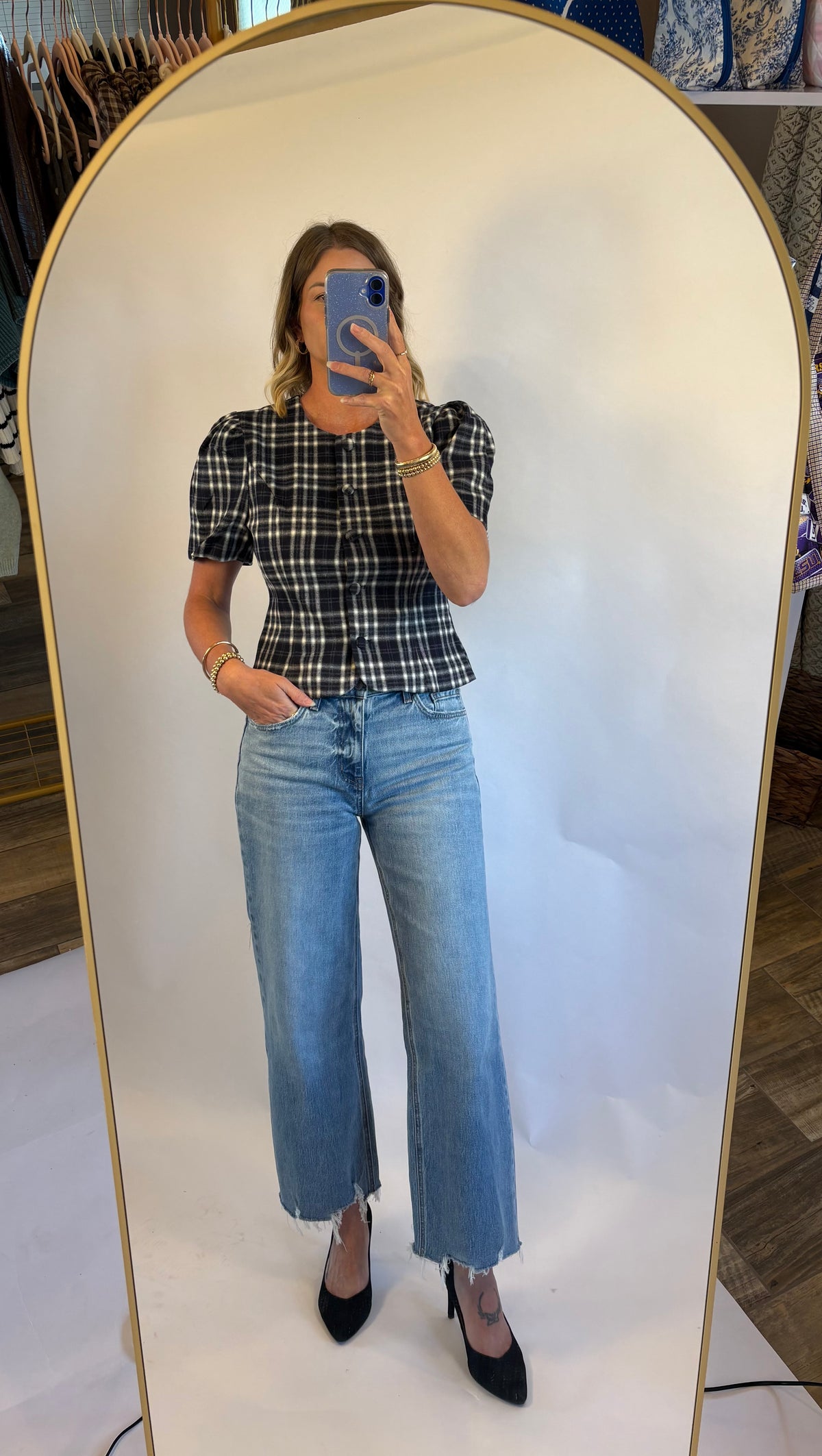 A woman wearing the Madilyn blouse in a blue plaid featuring a puff sleeve, button front and fitted silhouette