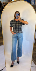 A woman wearing the Madilyn blouse in a blue plaid featuring a puff sleeve, button front and fitted silhouette