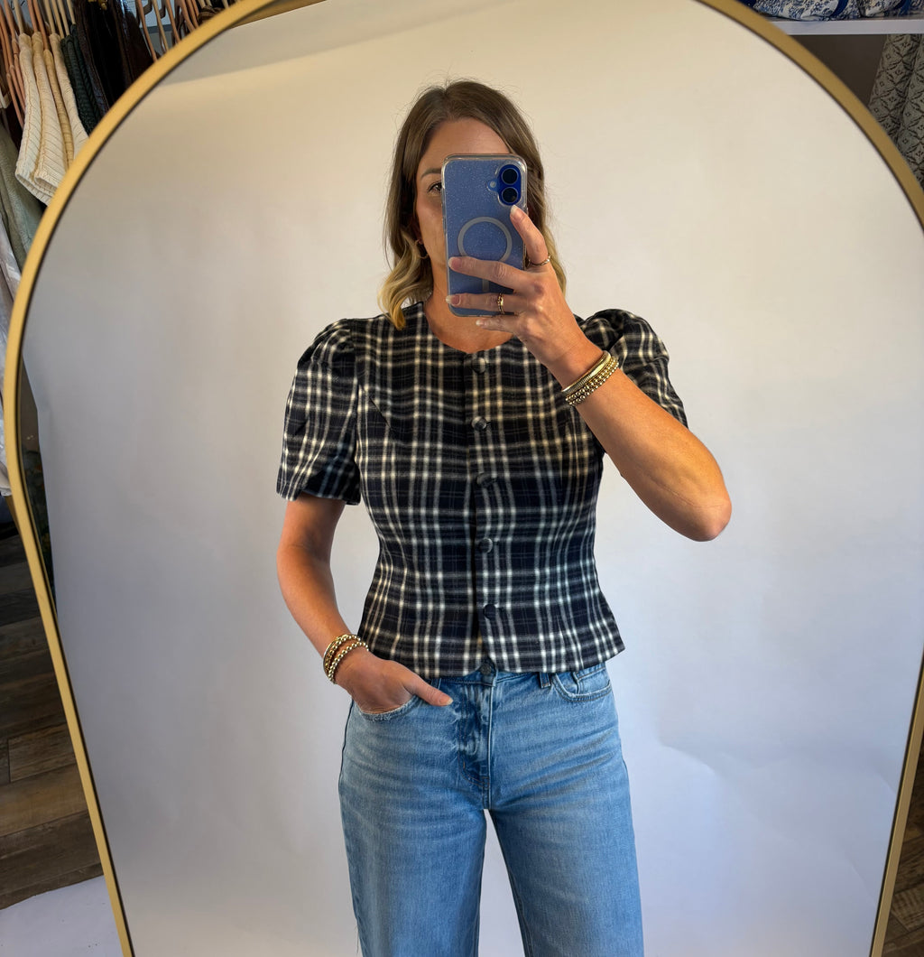 A woman wearing the Madilyn blouse in a blue plaid featuring a puff sleeve, button front and fitted silhouette