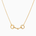 A gold horsebit necklace with a delicate cable chain, displayed against a clean white background.