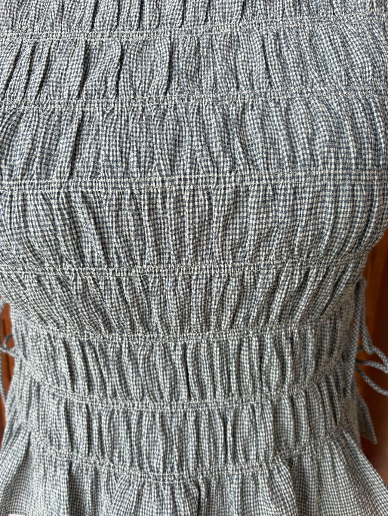 brooke & co blue haven top blue smocked sleeveless top with peplum hem and fitted bodice bow ties on the side close up view
