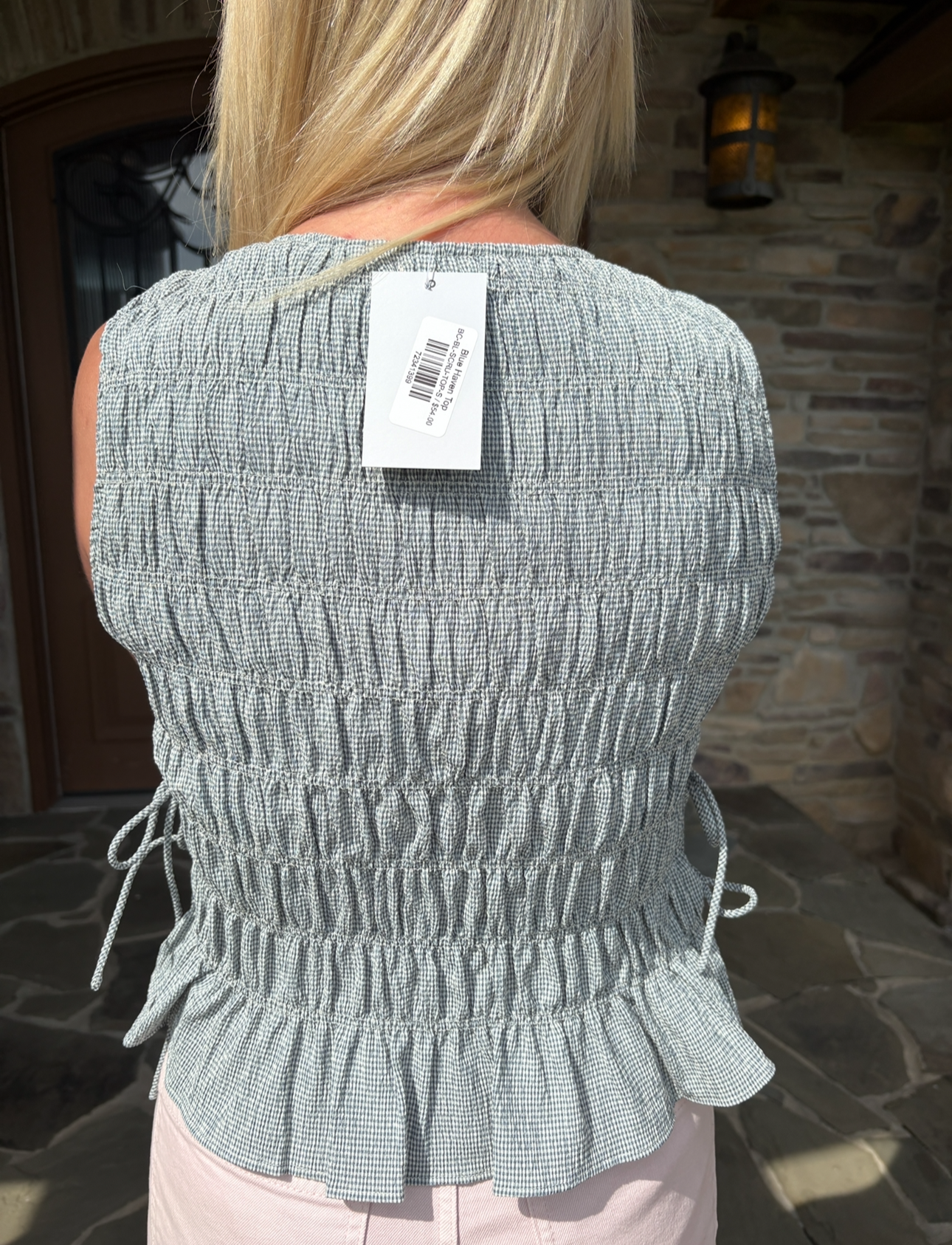 brooke & co blue haven top blue smocked sleeveless top with peplum hem and fitted bodice bow ties on the side back view