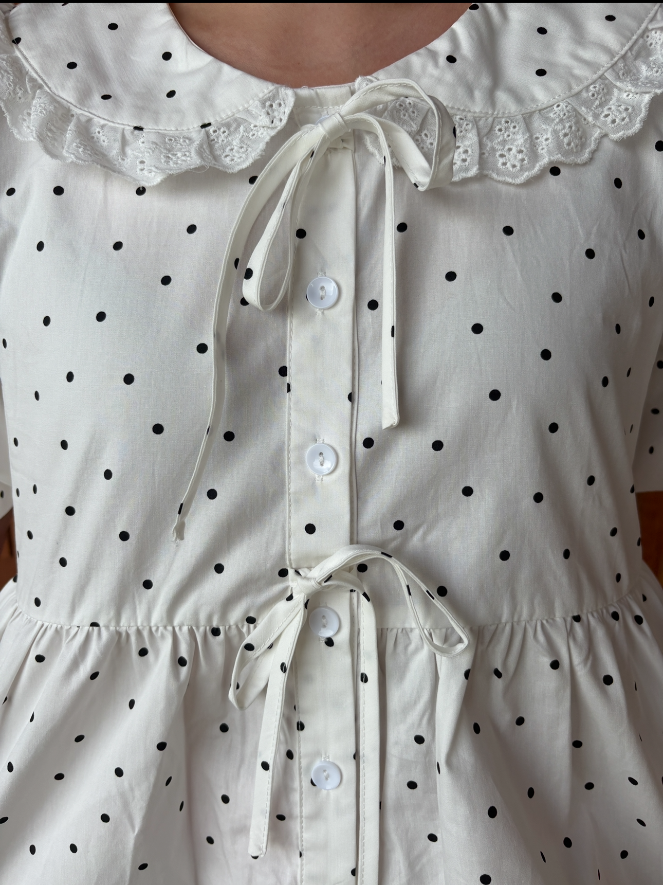 brooke & co polka dot darling white and black polka dot babydoll top with puff sleeves and tie neckline, flowy fit, close up view